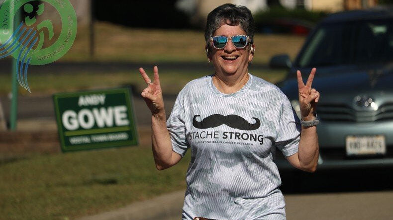 Runners sprinting to the finish at Stache Strong 5K in Vestal, NY with cheering crowd and visible bib numbers