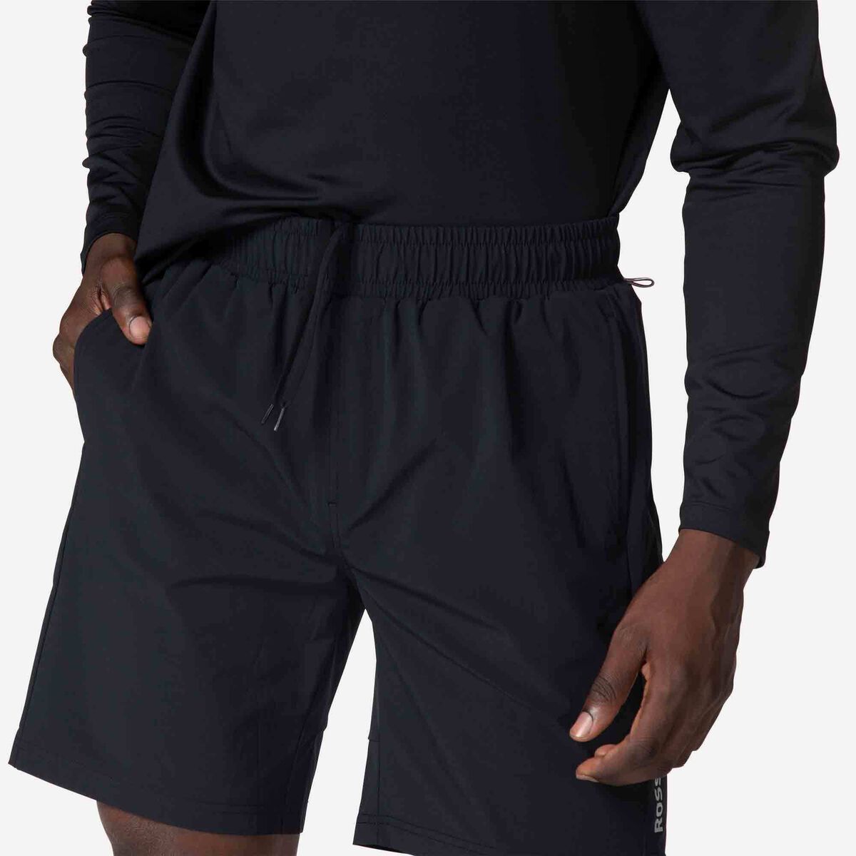 Person wearing black athletic shorts and long-sleeve shirt on a white background