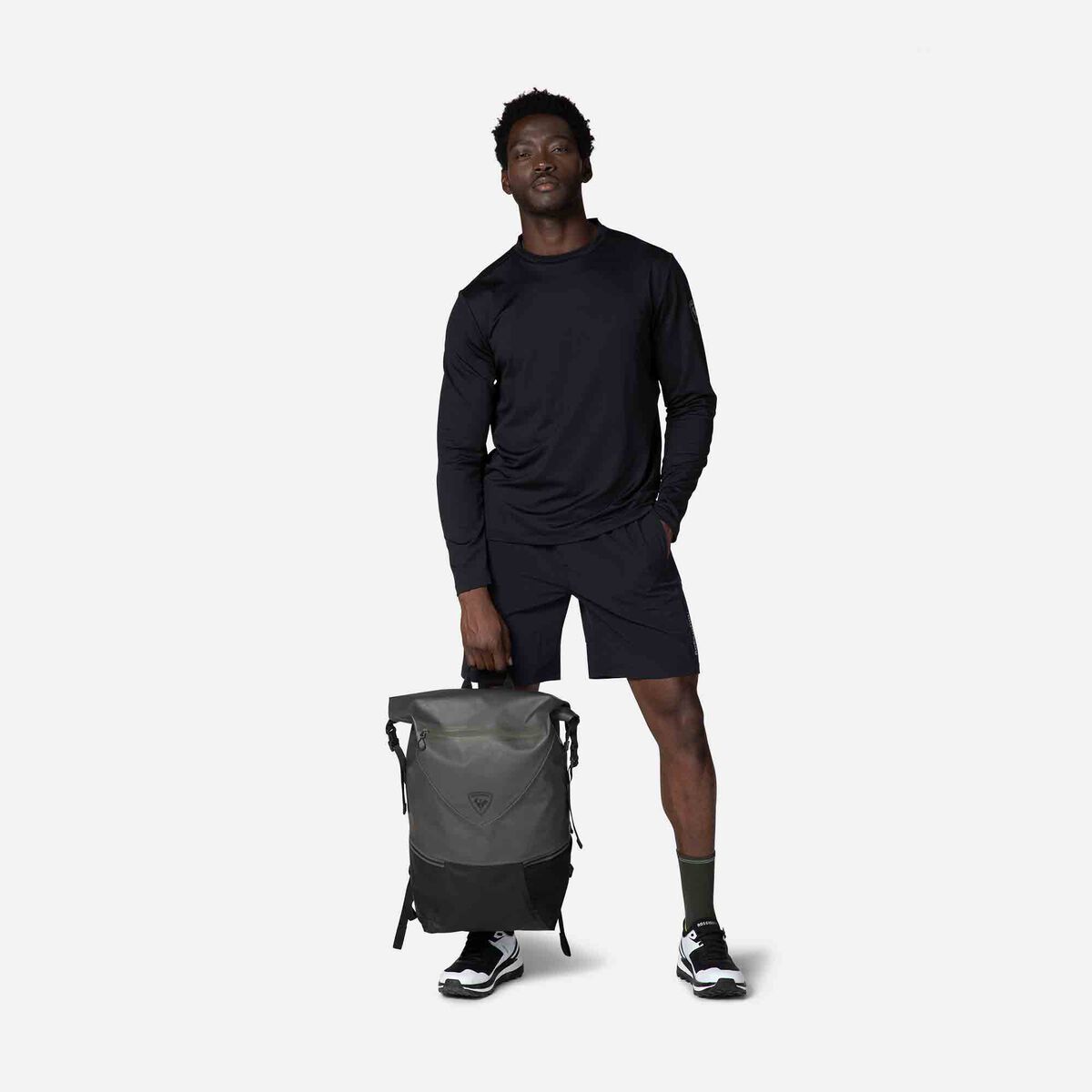 Man holding a gray backpack against a white background
