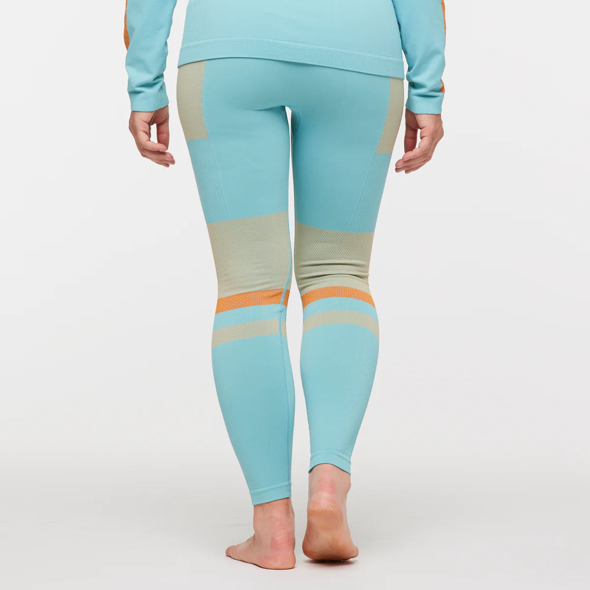 Women's Cotopaxi Debajo Seamless Baselayer Tights. Blue, tan, and orange pattern. Back view.
