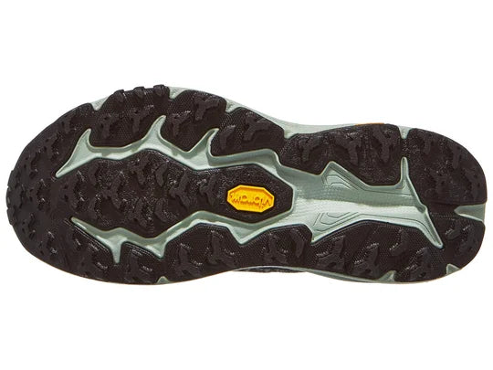 Pair of women's Hoka Speedgoat 6 shoes in Black/Aloe Vera, outsole view.