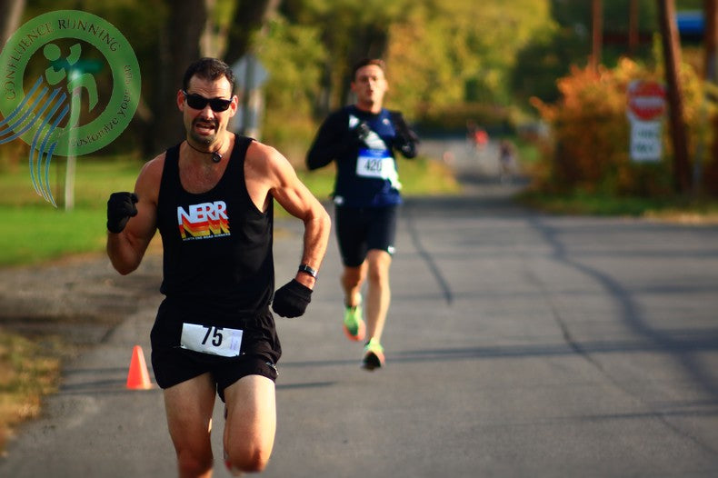 Steve Esposito drives to the OctoberFast 5K finish in Endicott, NY—intense race face—another runner right on his heels at the line.