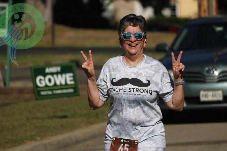 Runners sprinting to the finish at Stache Strong 5K in Vestal, NY with cheering crowd and visible bib numbers