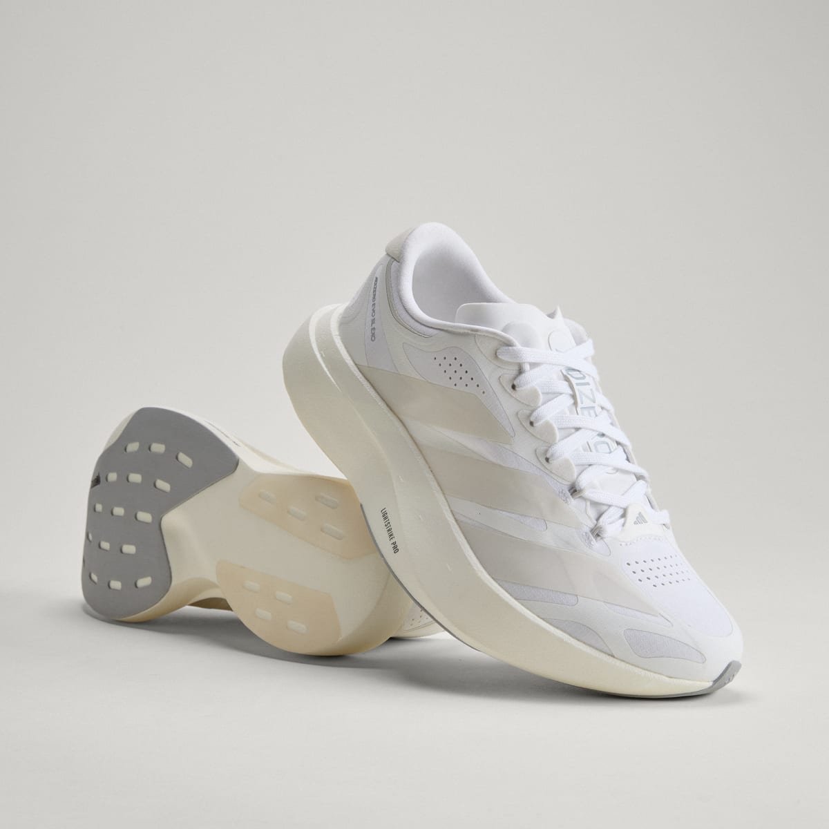 Adidas Adizero Evo SL Exo women's running shoe in Cloud White/Zero Metalic/Core White — angled pair with outsole visible