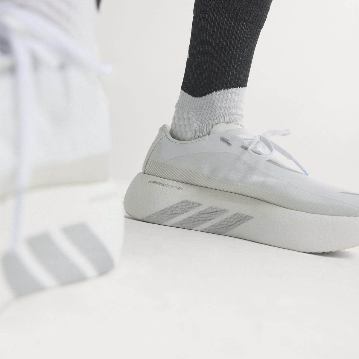 Adidas Hyperboost Edge men's running shoe in Cloud White/Silver Metallic/Zero Metallic — on-foot side detail.