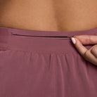 Women's Nike Dri-FIT Mid-Rise 2.5-inch Running Shorts in Pink Rise, zippered waistband pocket detail.