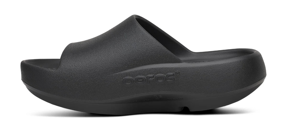 Unisex Oofos OOahh PLUS Slide in Black, medial side view.