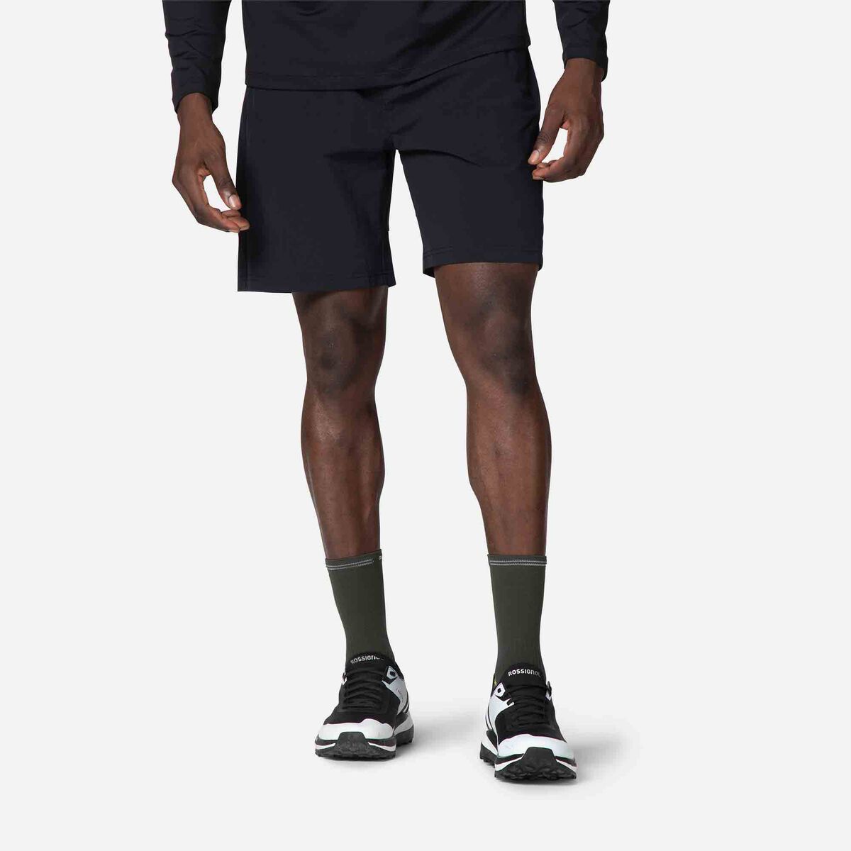 Person wearing black athletic shorts and black shoes on a white background