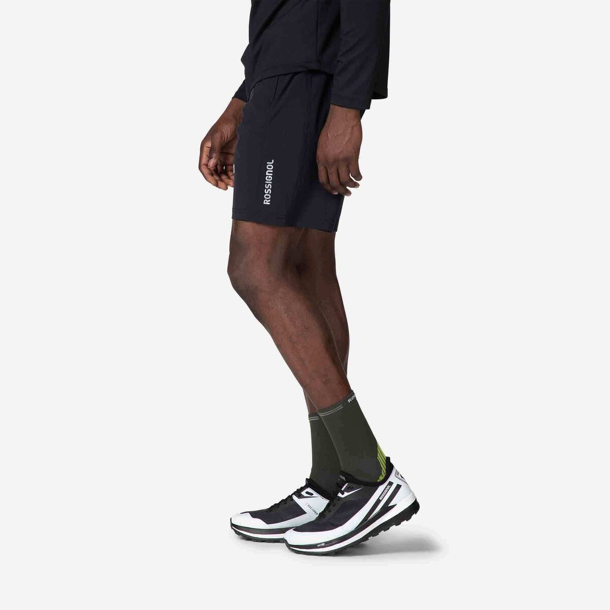 Person wearing black athletic shorts, black socks, and white running shoes on a white background