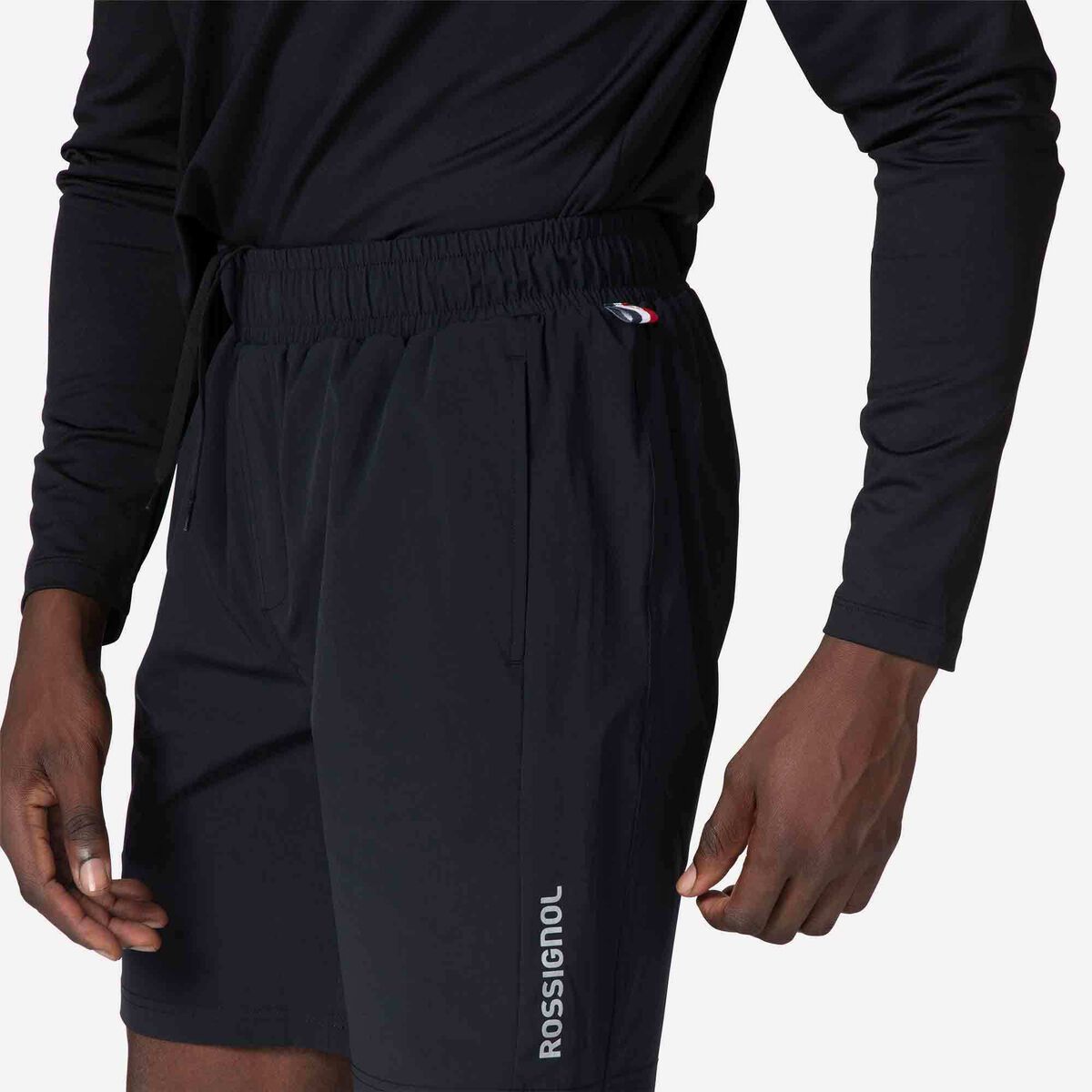 Person wearing navy blue athletic shorts with a visible brand logo on a plain background