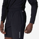 Person wearing navy blue athletic shorts with a visible brand logo on a plain background