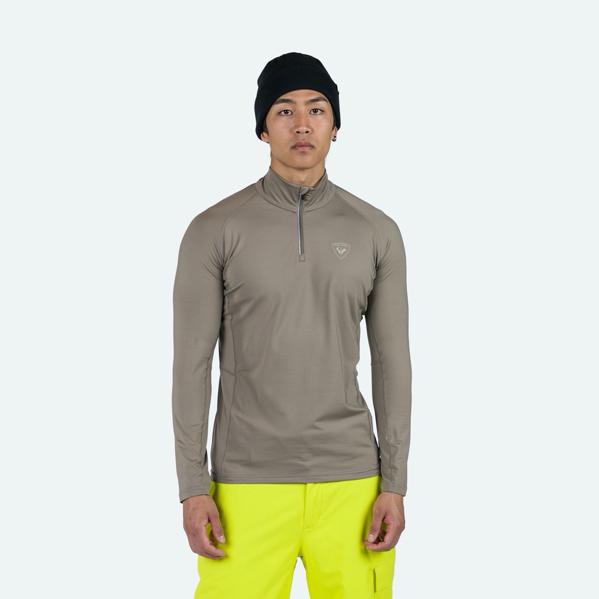 Person wearing a brown long-sleeve shirt and bright yellow pants on a white background
