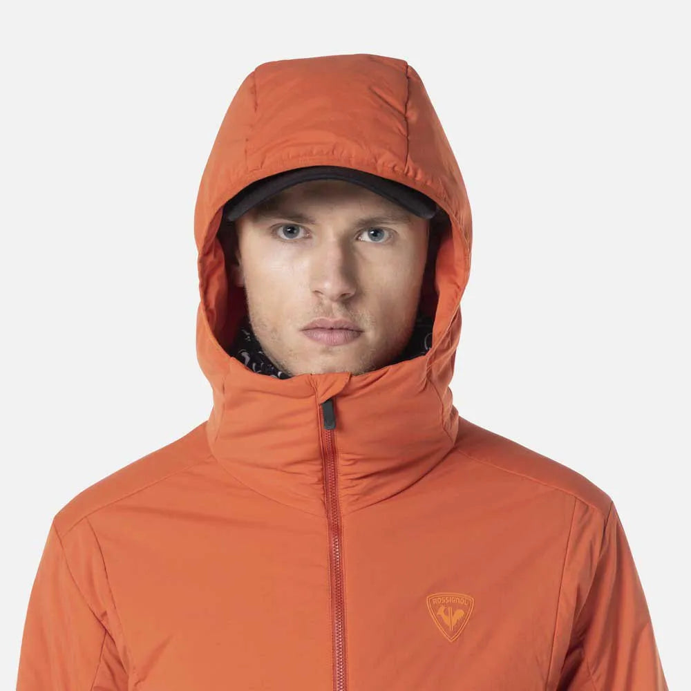 Person wearing an orange hooded jacket with a brand logo on a light gray background