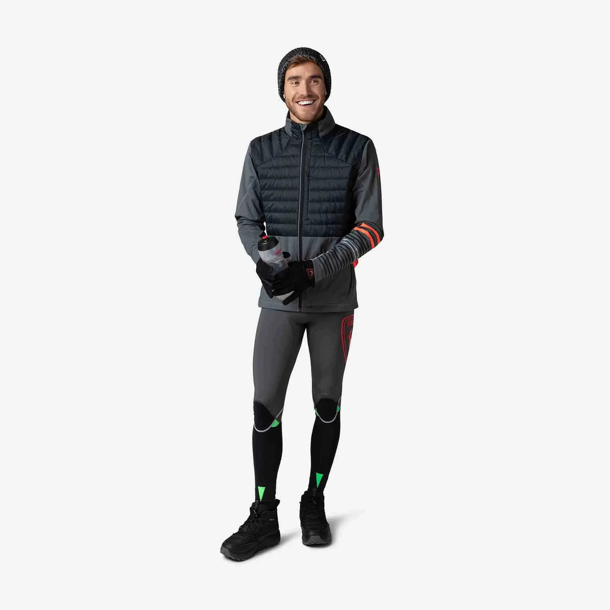 Person wearing a gray insulated jacket and black leggings with green accents on a white background