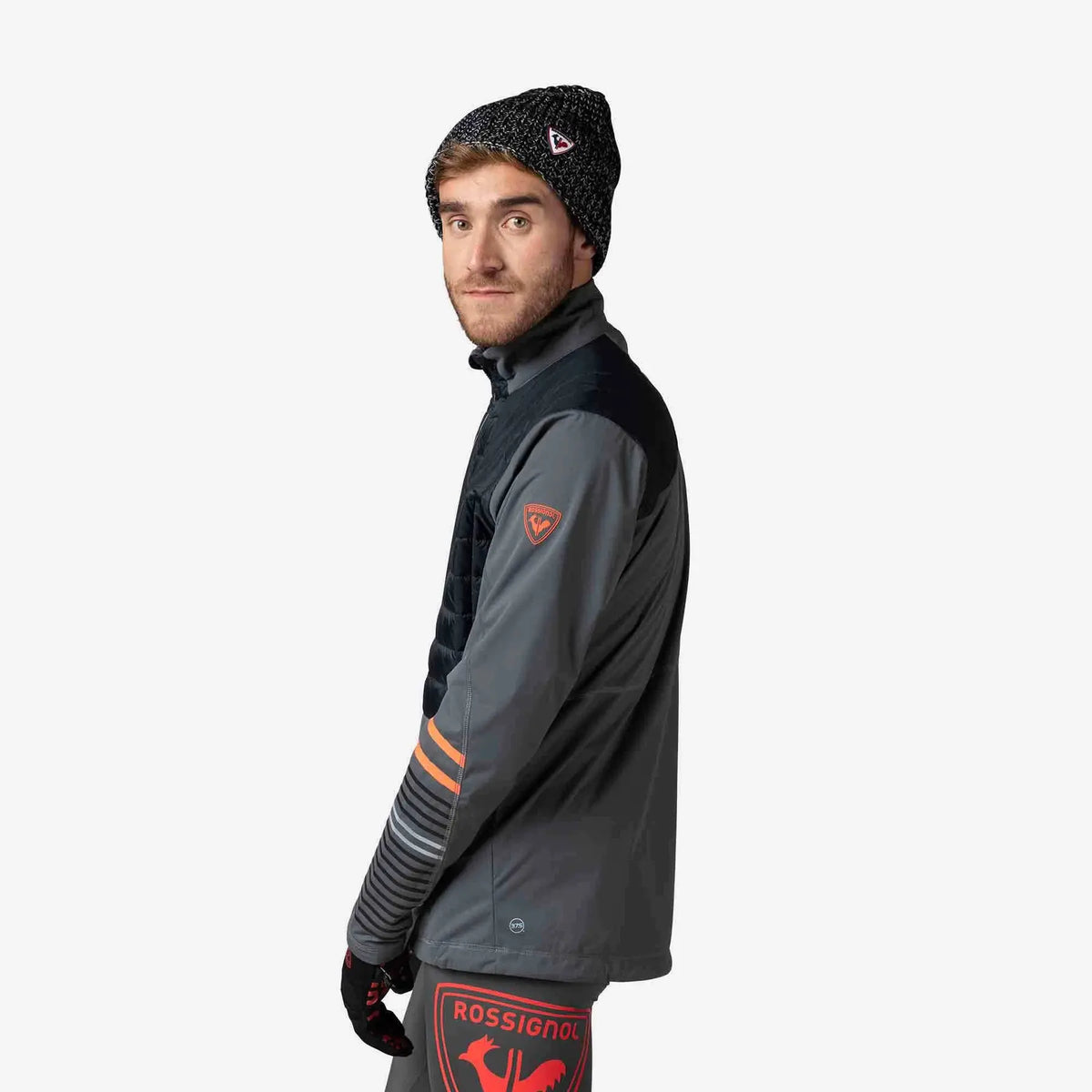 Person wearing a gray jacket with orange accents and a black beanie on a white background