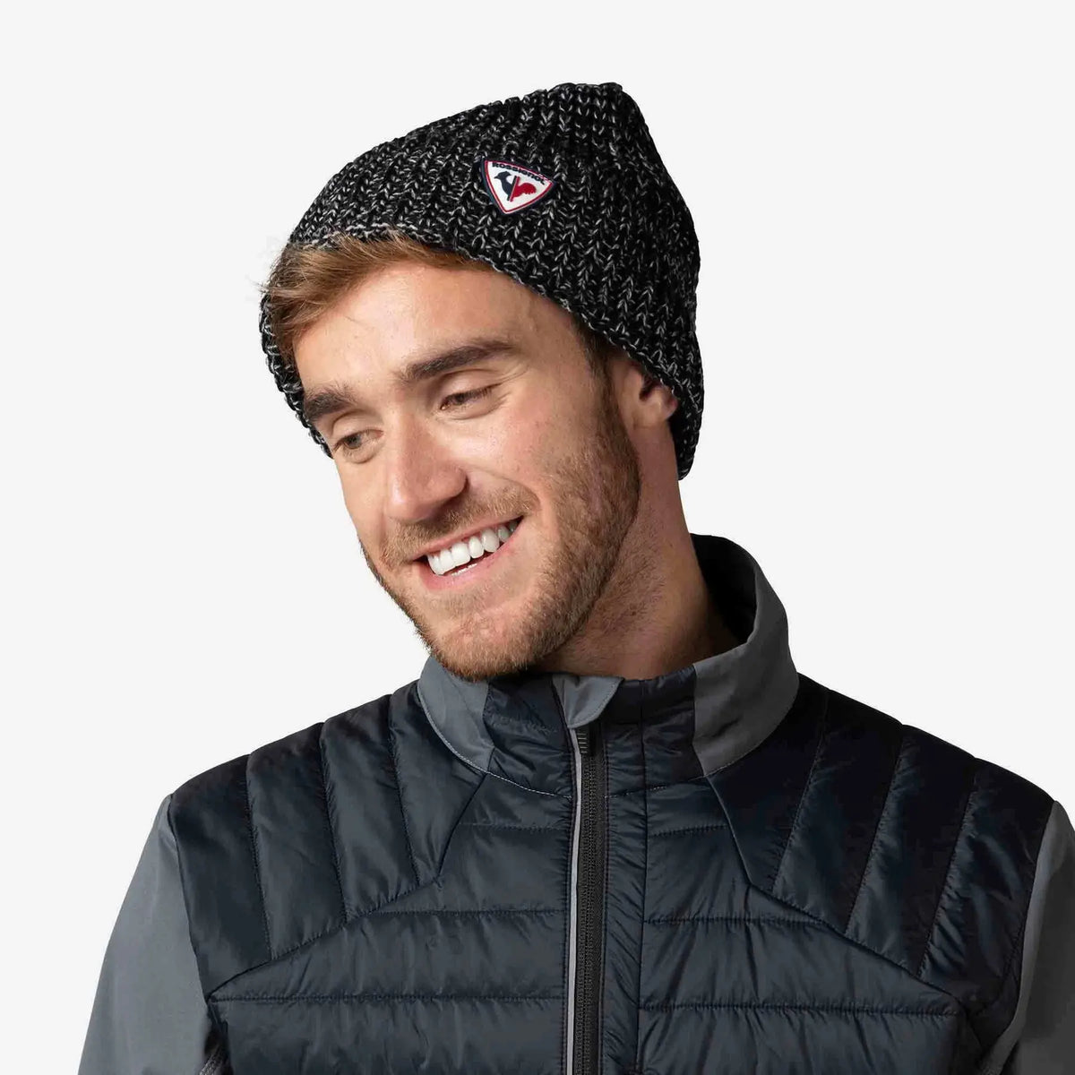 Man wearing a black knit beanie with a logo on a white background