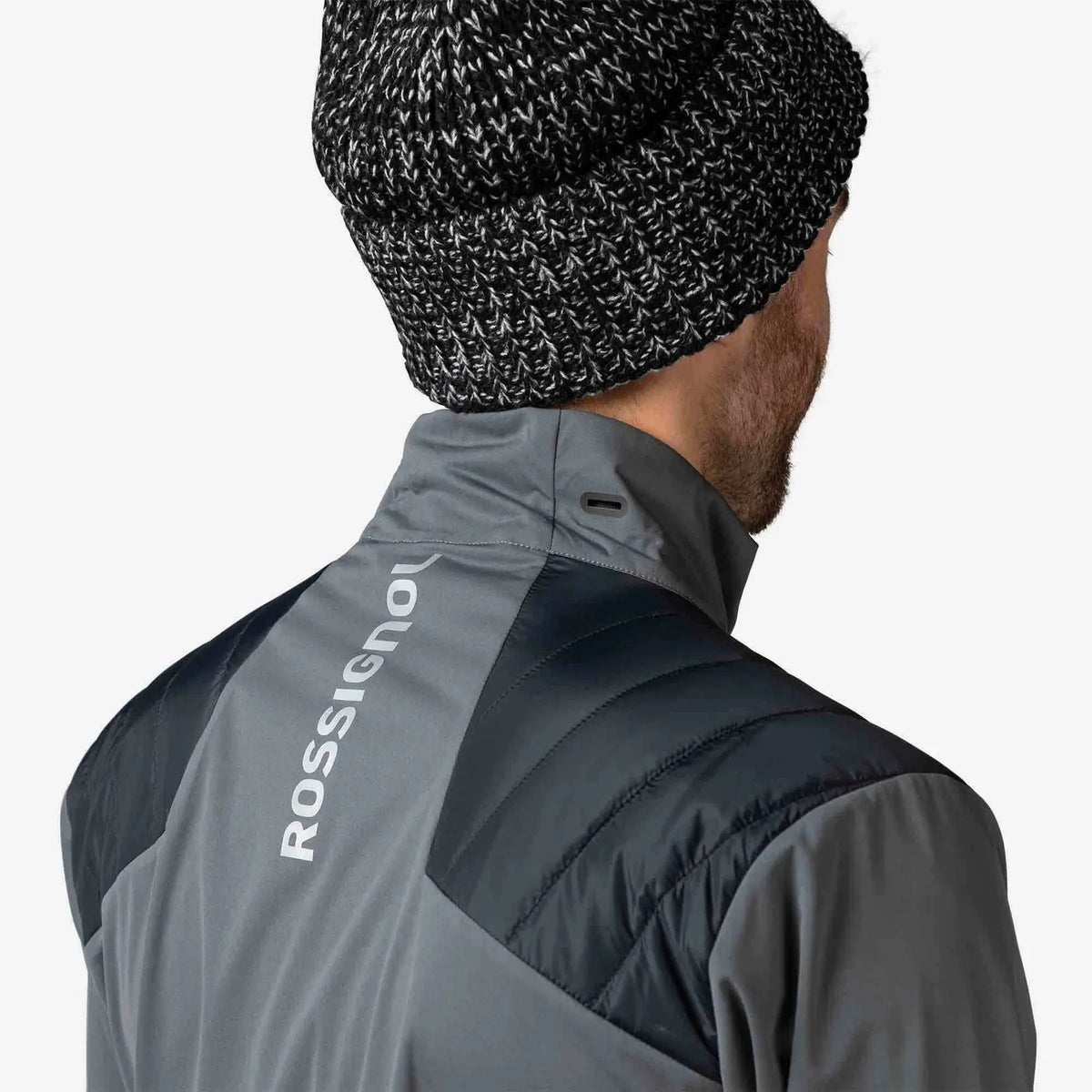 Person wearing a gray and black jacket with 'ROSSIGNOL' branding on the back, against a white background.