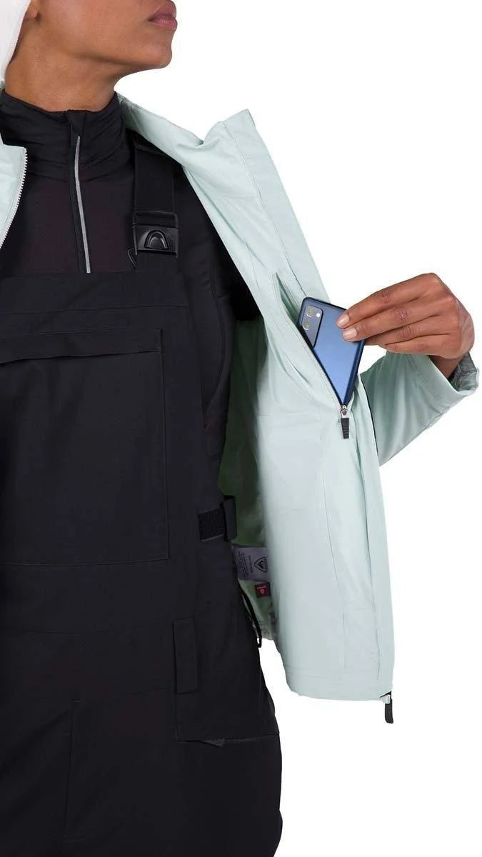 Person wearing a light blue jacket with a phone in the pocket on a white background