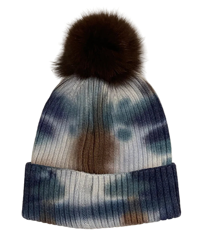 Knitted beanie with a fur pom-pom on a textured white background