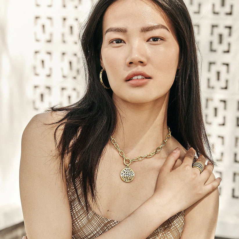 Woman wearing gold jewelry against a decorative wall