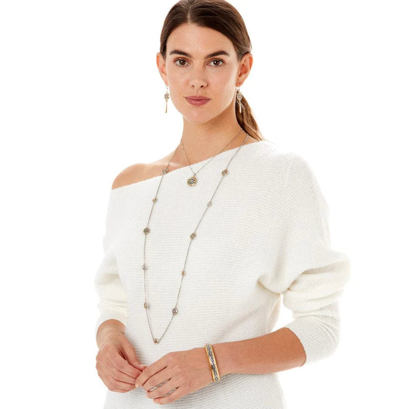 Woman wearing a white sweater with a long necklace and bracelet on a white background
