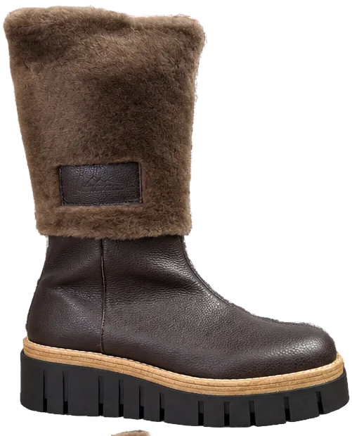 A dark brown leather ankle boot with a fluffy brown shearling collar and a chunky black lug sole with a tan midsole, shown against a plain white background.