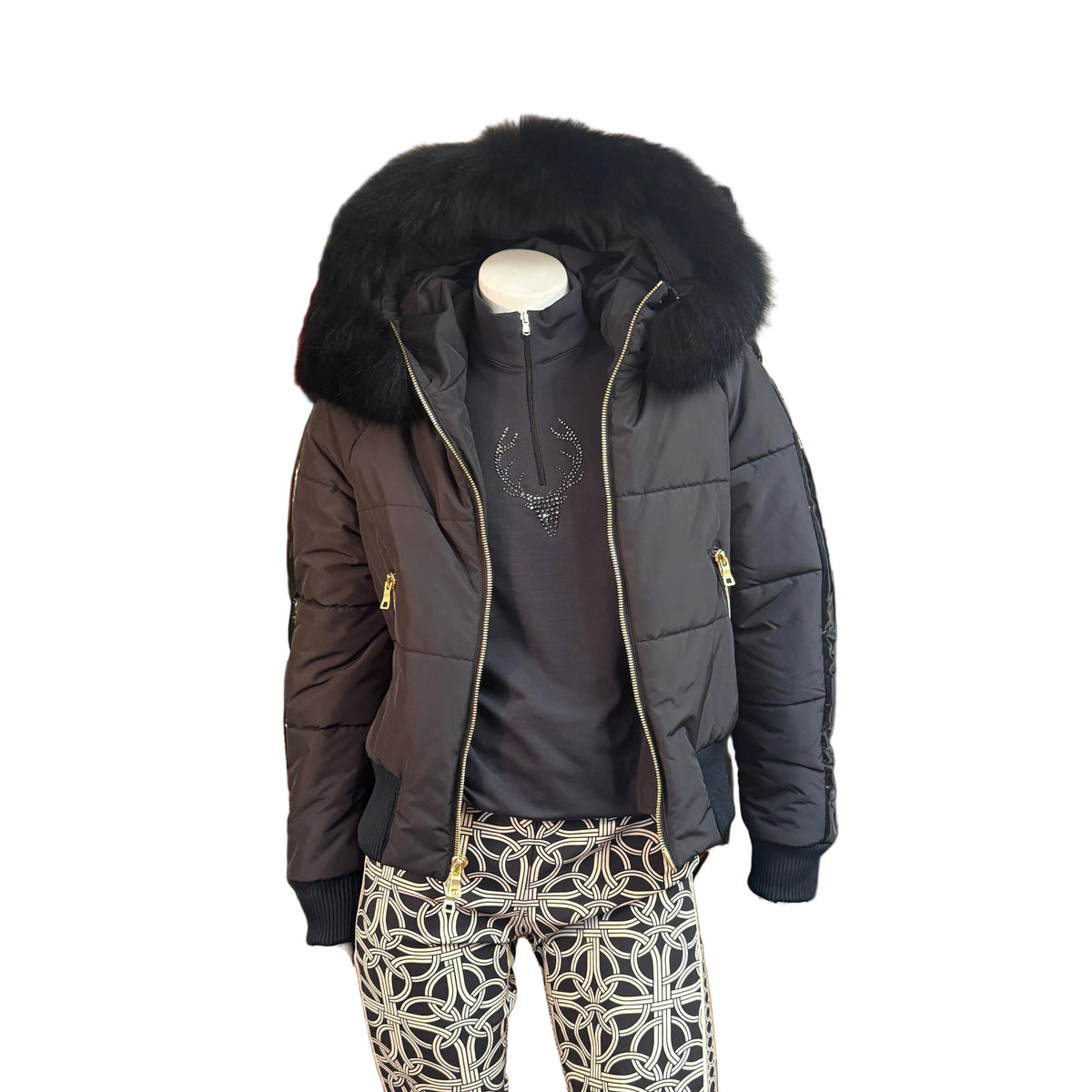 A black puffer jacket with a large black fur-trimmed hood, styled on a mannequin with a dark gray top and beige-and-black geometric print pants against a white background.