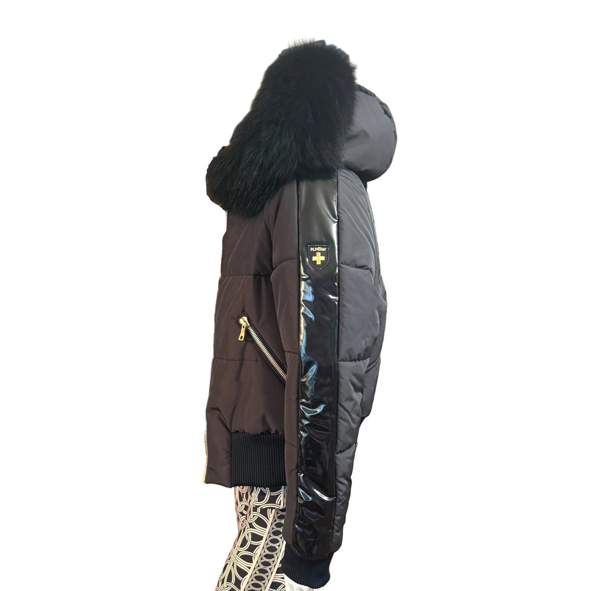 A side-profile view of a women's puffer jacket with a large black fur-trimmed hood, dark brown body panels, black side panels, and a black patent sleeve, shown against a plain white background.