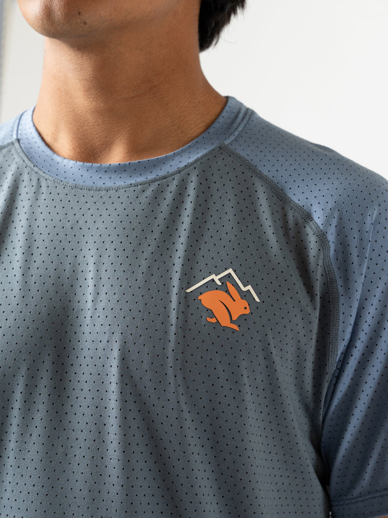 Men's Rabbit EZ Tee Perf SS Trail. Grey and blue color. Orange logo. Front view, up close.