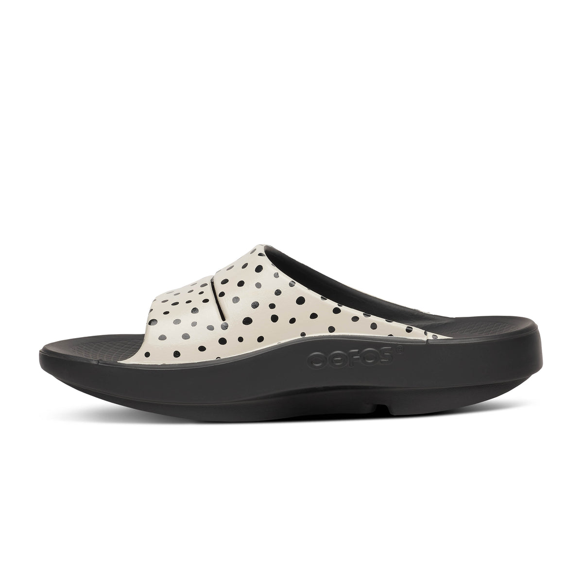 Oofos Ooahh Limited Slide. Black and tan colorway with dotted pattern. Medial view.