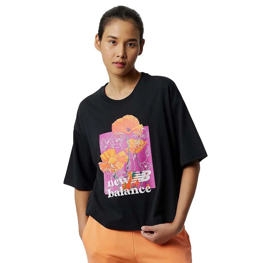 Women's New Balance Essential Bloom Tee. Black with floral pattern in the middle. Front view.