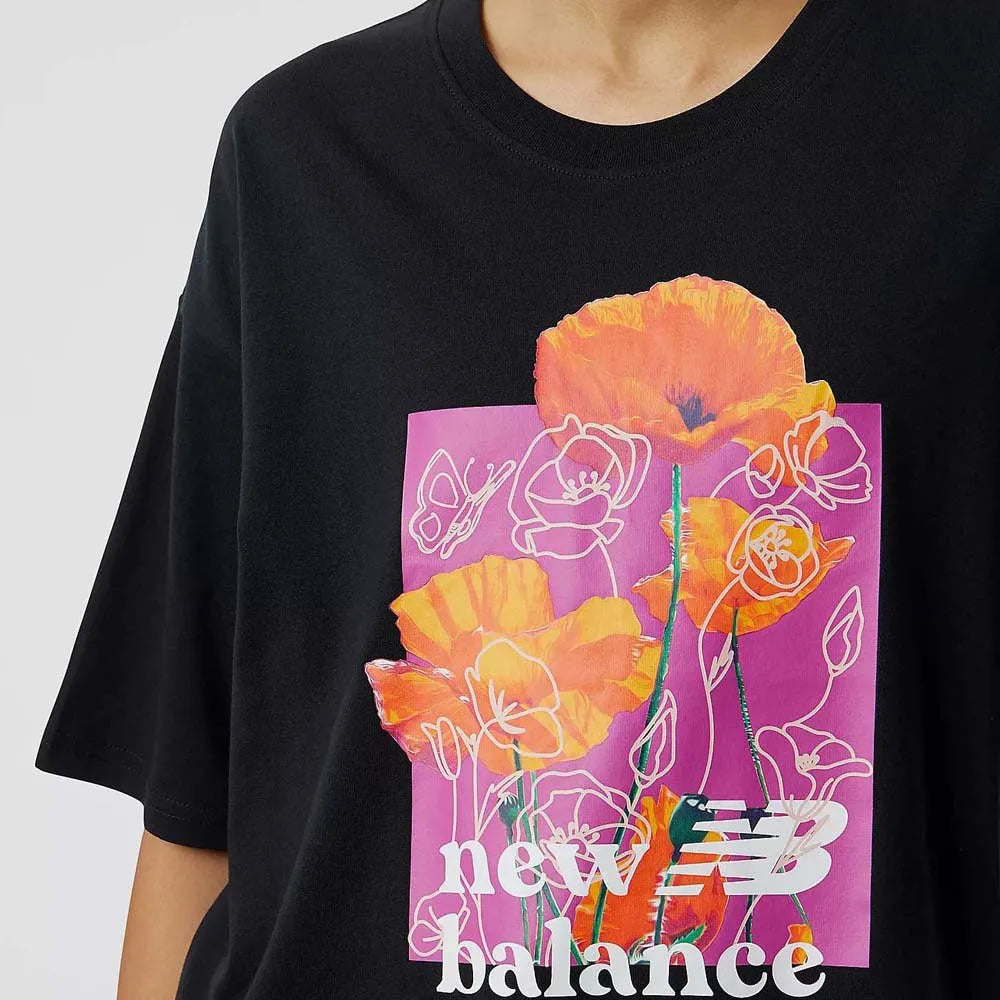 Women's New Balance Essential Bloom Tee. Black with floral pattern in the middle. Front view.