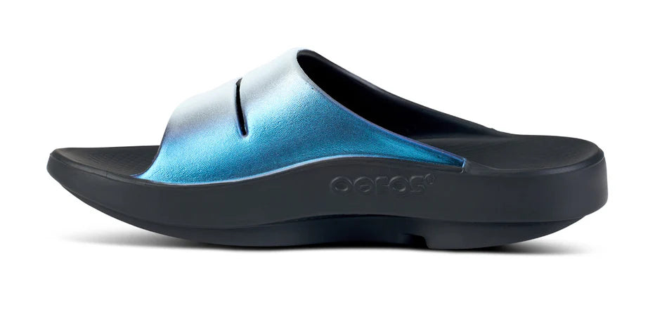 Women's Oofos Ooahh Luxe Slide. Blue Strap. Black midsole. Medial view.