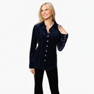A woman modeling a navy velvet button-down shirt with metal buttons and long sleeves.